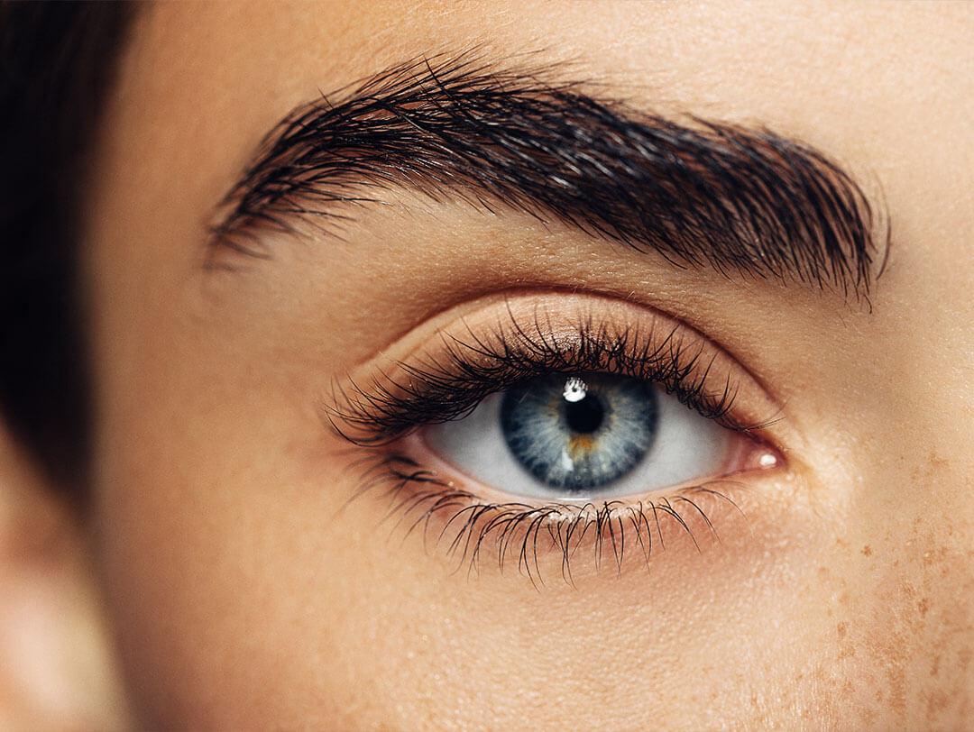 A beautiful woman with fair skin, thick brows, and blue eyes wearing clump-free mascara